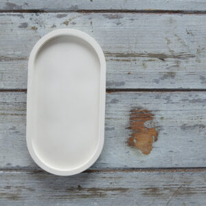 Gipsz tálca dekoráció közepes méretben, skandináv stílusú enteriőrökbe. A sima, kézzel készült felület rusztikus fa háttér előtt látható, kiemelve a termék természetes eleganciáját és sokoldalú felhasználhatóságát.