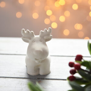 Beltéri gipsz dísztárgy: egy elegáns, álló szarvas figura agancsokkal, matt fehér színben. Letisztult, minimalista design, amely természetes eleganciát kölcsönöz a helyiségnek, rusztikus fa felületen fotózva.