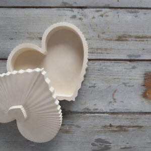 Beltéri gipsz dísz: egy szív alakú, fedeles doboz matt fehér kivitelben. A letisztult forma tökéletes apró ékszerek tárolására vagy önálló dekorációs elemként a fésülködőasztalon.