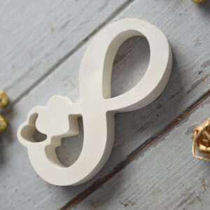 Perspektivikus közeli kép a Végtelen gipsz díszről, amely kiemeli a lágy íveket és a sima, matt textúrát. Modern lakberendezési kiegészítő, amely szimbolikus jelentése miatt kiváló ajándék is lehet.