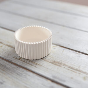 Kézzel készült, finoman bordázott oldalú fehér gipsz mécsestartó, amely elegáns kiegészítője a modern otthoni dekorációnak.