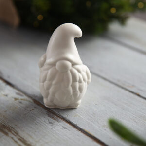 Szemből fotózott gipsz törpe figura, mélyen a szemébe húzott kötött mintás sapkával és dús szakállal.