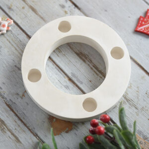 Perspektivikus kép egy elegáns fehér gipsz gyertyatartóról, karácsonyi kiegészítőkkel és piros bogyós ággal díszítve.