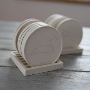 Háromnegyedes nézet egy kézzel készült horoszkóp alátétről, rusztikus fa felületen, kiemelve a gipsz tiszta textúráját.