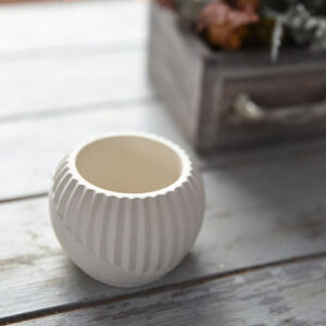 Hangulatkép a MiraStone gipsz mécsestartóról felülnézetből. A termék mellett egy pasztell masni és egy virágokkal teli antikolt fadoboz látható, sugallva a romantikus és modern lakberendezési stílust.