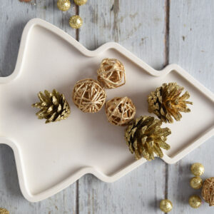 Fenyő alakú gipsz tálca arany színű dekorációs tobozokkal és gömbökkel díszítve, hangulatos tálalási ötlet.